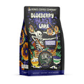The front of a 12 ounce bag of Bones Coffee Company Blueberry Blast Cake flavored coffee. Its flavor is blueberry pancakes. The art shows a skeleton using a bow and arrow with a blueberry on the tip shooting at pancake targets on it.