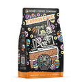 The front of a 12 ounce flavored coffee bag named Carrot Cake. It showcases a skeleton wearing rabbit ears laying down on a slice of cake holding carrots on its art.