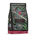 The front of a 12 ounce bag of Bones Coffee Company Guatemala coffee. It has notes of milk chocolate, caramel, and citrus flavors. There is a bird sitting on a branch with other birds flying around on the art.