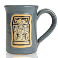 The front of the Bones Coffee Company Maximus hand thrown mug with the Valiant Vanilla art on the golden medallion. It is inspired by Zenimax and Amazon’s Fallout show. The mug is gray colored.