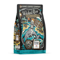 The front of a 12 ounce bag of Wicked Rum Barrel Aged Coffee. It has a skeleton in a pirate hat on a beach drinking coffee from a cup on a barrel of rum. It also has the logo of Wicked Dolphin on it.