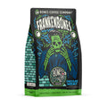 The front of a 12 ounce bag of Bones Coffee Company Frankenbones coffee. Its flavor is chocolate hazelnut, and it has a green skeleton with blue and green electricity scattered around on the art.