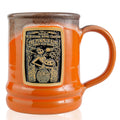 The front of the Bones Coffee Company Pumpkin King hand thrown mug with Jack Skellington on the golden medallion. The mug is orange colored with a black and white glaze on top.