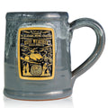 The front of the Bones Coffee Company Ruff Weather hand thrown mug with Zero the dog from Tim Burton’s The Nightmare Before Christmas on the golden medallion. The mug is grey colored with a black and white glaze on top.