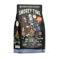 The front of a 12 ounce bag of Bones Coffee Company S’morey Time decaf coffee. Its flavor is s’mores, and it has a skeleton holding a flashlight around a campfire with bigfoot and a werewolf on the art.